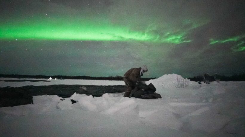Un paracadutista americano ripiega il paracadute sotto l'aurora boreale (US Army)