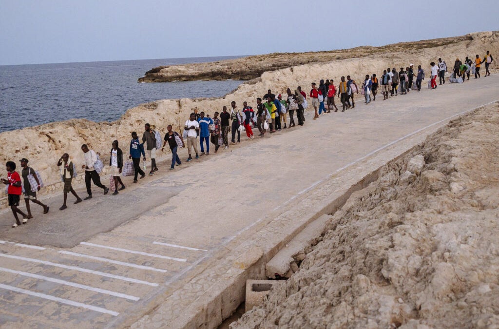 Migranti camminano in fila sull’isola di Lampedusa