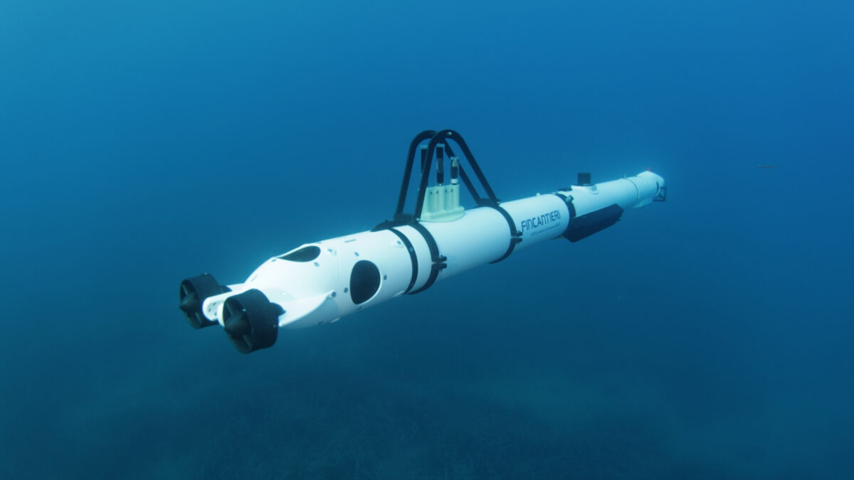 Un drone sottomarino bianco con il logo Fincantieri e eliche anteriori che naviga nell'acqua blu profonda