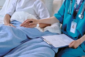 paziente in un letto d'ospedale e medico che gli tiene la mano