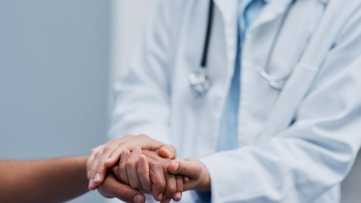 Medico tiene la mano di un paziente durante una visita