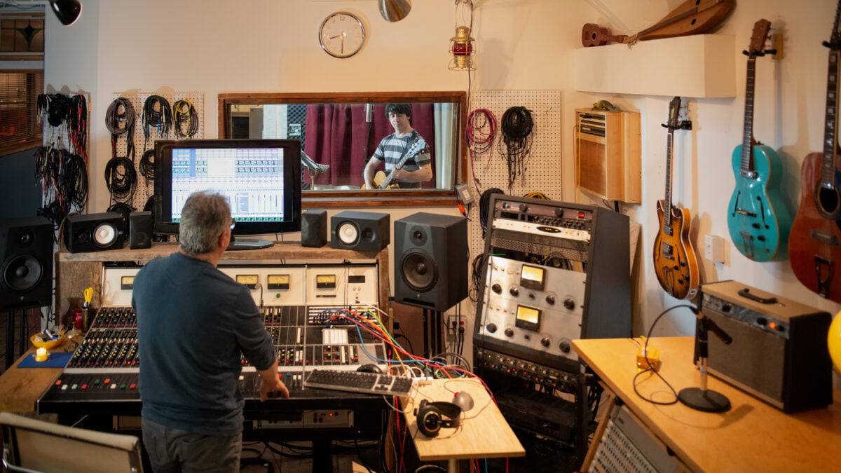 Musicista che suona la chitarra in uno studio di registrazione analogico