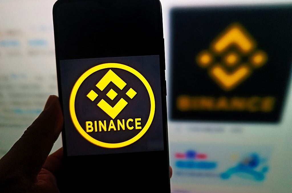 Un utente consulta il sito web di Binance al computer e il logo della piattaforma sullo smartphone