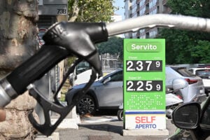 Pompa di benzina in una stazione di servizio con il cartello dei prezzi dei carburanti