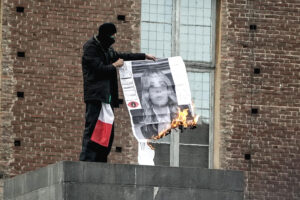 Manifestante brucia una fotografia di Giorgia Meloni durante il corteo a Torino del 24 ottobre 2026