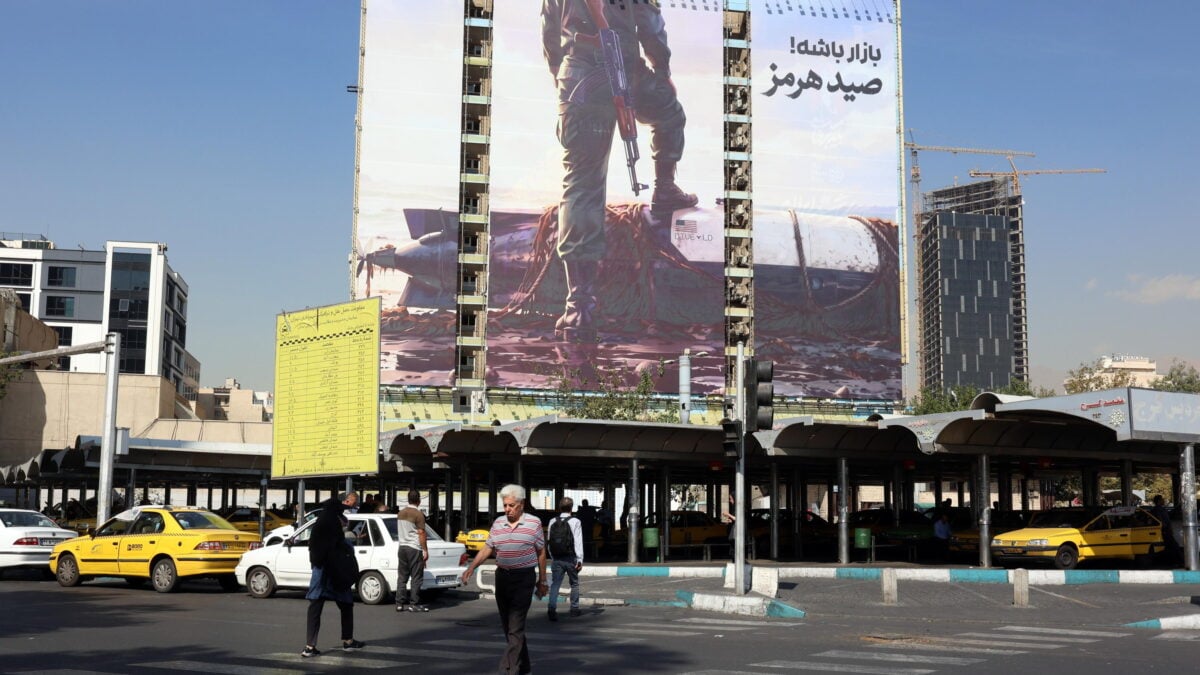 Persone passano davanti a un cartellone antiamericano a Vanak Square, a Teheran