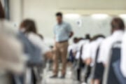 Insegnante sfocato sorveglia gli studenti impegnati in un esame in aula