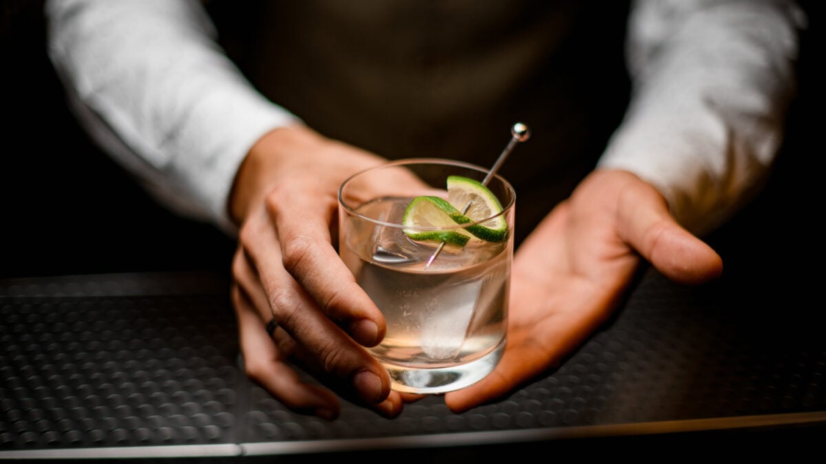 Barista tiene in mano un bicchiere con una bevanda alcolica fredda